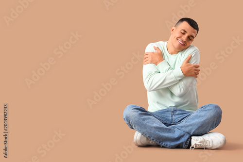 Young man hugging himself o...