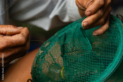 Cuadro en lienzo Detailed shot of senior hands pulling a nylon string to fix a green mesh fishing