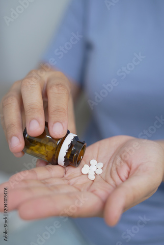 woman is holding headache pills to reduce her fever