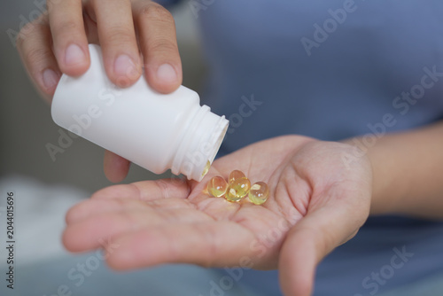woman is holding headache pills to reduce her fever
