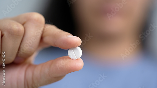 woman is holding headache pills to reduce her fever