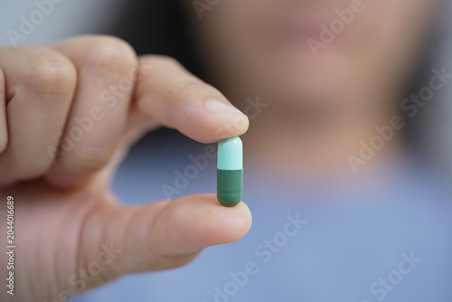 woman is holding headache pills to reduce her fever