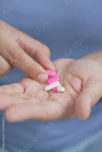 woman is holding headache pills to reduce her fever