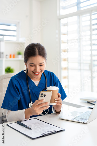 Female doctor using cell phone on coffee break at hospital.
