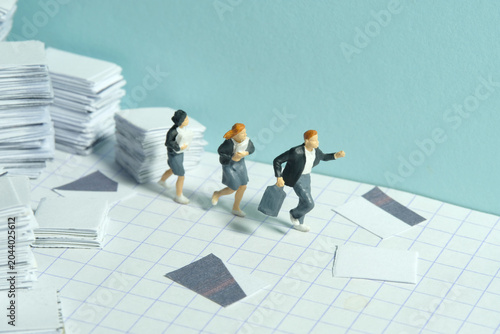 Miniature people toy figure photography. Homework concept. The group of pupil students running on paperwork task document pile stack