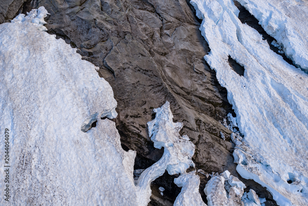 Fototapeta premium Aerial View Of Glacier Snow And Exposed Rock Crevasse On Alpine Slope In BC, Canada