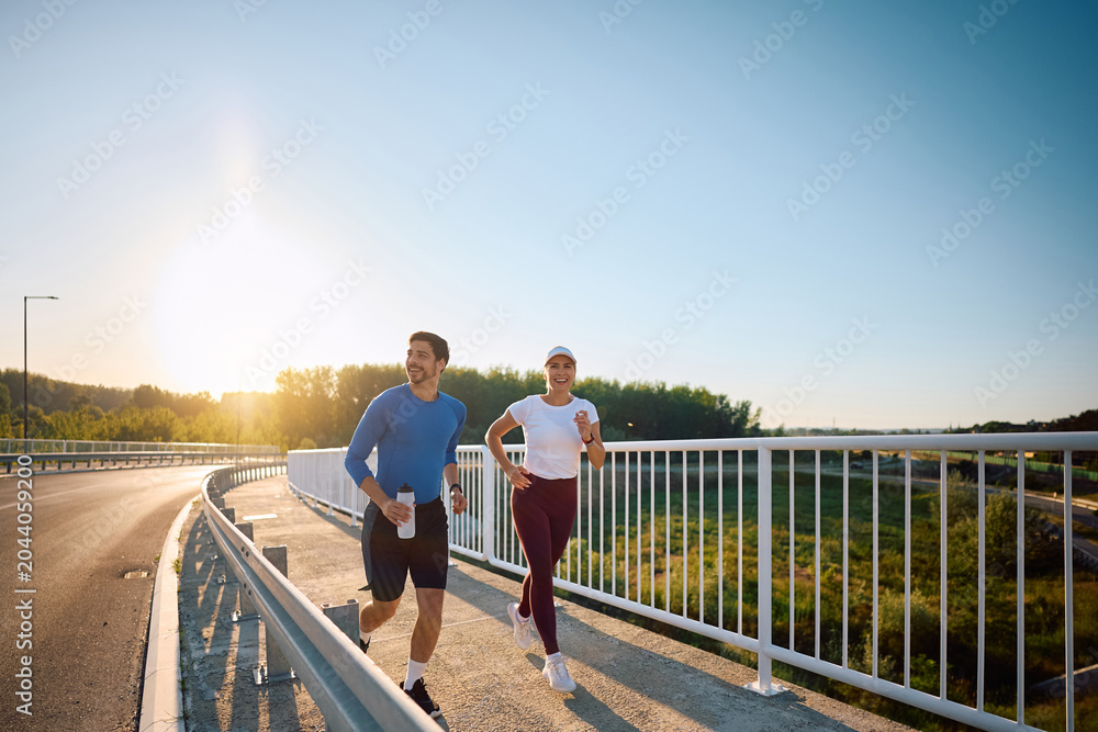 Naklejka premium Happy athletic couple enjoying in recreational running outdoors.