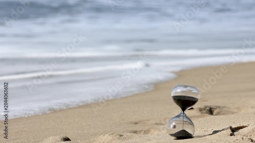 Hourglass on Sandy Beach by Ocean Shore