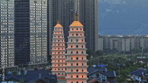 Illuminated Twin Pagoda Towers Among Modern High Rise Apartments at Dusk