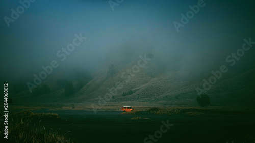 Obraz na płótnie An orange 4x4 vehicle in the middle of a heavy fog in the volcanic caldera of Mo