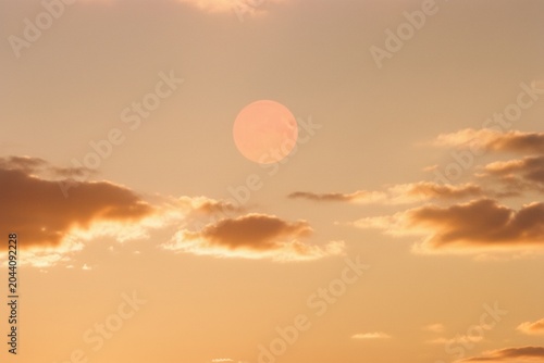 Golden sunset sky background with a glowing moon and soft clouds for spiritual meditation, holiday editorial and seasonal branding with copy space for text