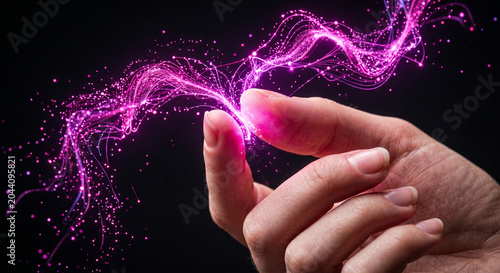 Human hand touching magical glowing pink energy dust and light trails on a dark background.