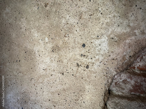 Rough concrete wall texture with exposed brick corner