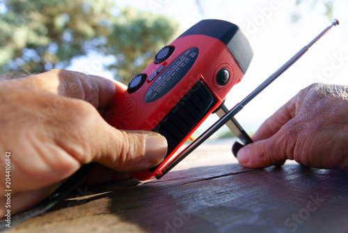 Billede på lærred Man's hands adjusting an emergency portable radio with solar panel and hand cran