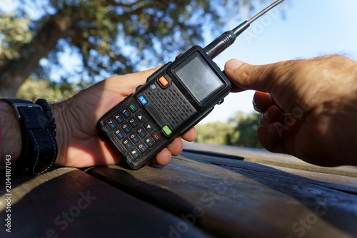 Billede på lærred Hands holding a portable radio transceiver, providing communication for outdoor