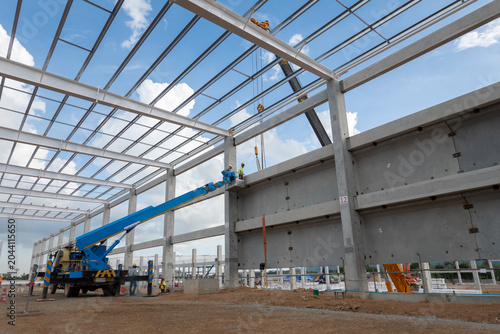 Schilderij op canvas Industrial Construction Site: A large-scale industrial building under construction, featuring a steel frame structure and concrete walls