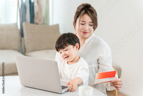 Fotografía A single mother is looking at her computer and bankbook while holding her child