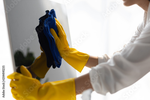 Young Asian cleaning woman uses a cloth to wipe clean a computer using cleaning solution in her home office.