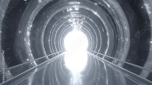 A bright light shines at the end of a metallic tunnel