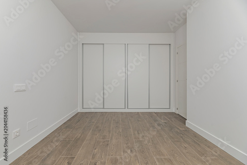 Bild auf Leinwand An empty Nordic-style bedroom with built-in wardrobes in natural wood, whose cle