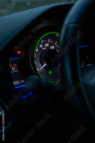 Car Speedometer Gauge and Instrument Cluster Behind Steering Wheel