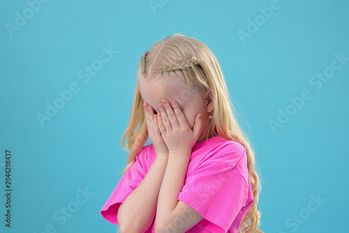 Upset frustrated kid showing sad negative emotions while covering her face