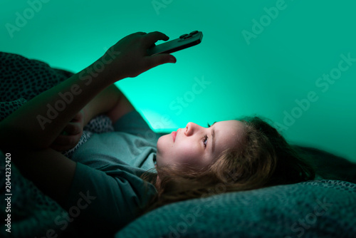 Billede på lærred Teenager relaxing with phone in bed at night