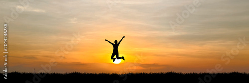 Schilderij op canvas A silhouette of a person jumping for joy against a vibrant sunset sky