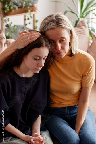 Obraz na plátně Caring mother sitting beside troubled teenage daughter on sofa, parent lovingly