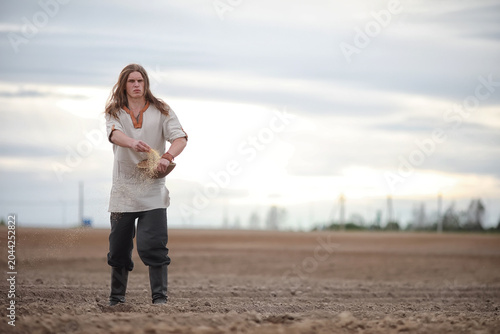Obraz na plátně A young peasant sows the field with grain