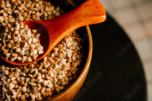 Bild auf Leinwand Healthy organic green buckwheat groats spooned into a rustic wooden bowl indoors