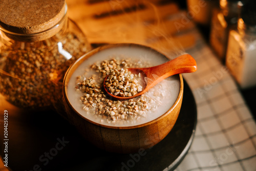 Tableau sur toile Steaming organic green buckwheat porridge in wooden bowl with spoon and groats j