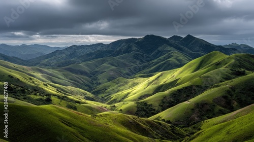 Sunlit, rolling green hills under dramatic, cloudy skies