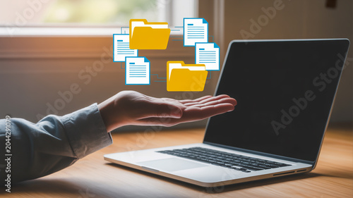 Hand holding digital files and folders connected to a laptop screen