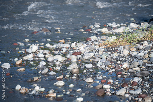 Konstfotografi Natural river bank with smooth grey stones pebbles and fast flowing water backgr