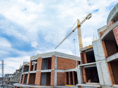 Fényképezés Construction site in progress with a crane lifting materials and building struct
