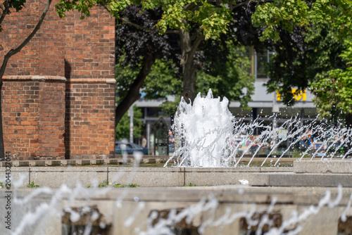 Quadro su tela A fountain splashes beside the red brick Rotes Rathaus in Berlin