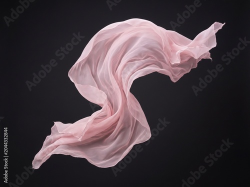 Elegant flowing pink silk fabric swirling in motion against dark background