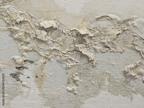 Grungy background texture of peeling wall paint with water damage stains and cracks.