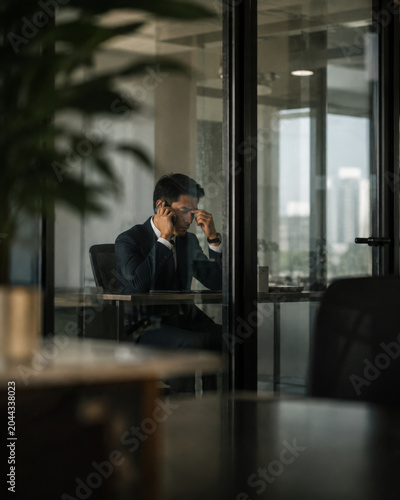 Stressed businessman sitting in office feeling exhausted