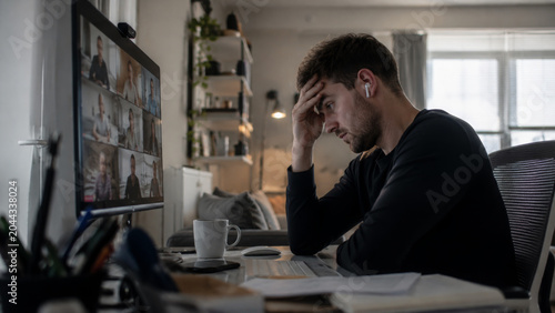 Stressed man feeling exhausted during video conference call
