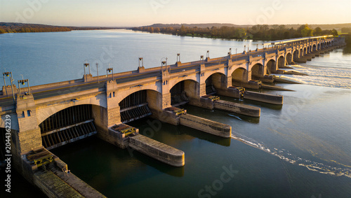 Obraz na plátně Aerial view of a concrete river dam with multiple spillway gates and flowing wat