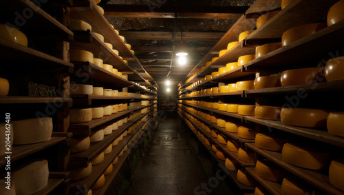 Foto A dimly lit underground stone cellar with long rows of wooden shelves holding ma
