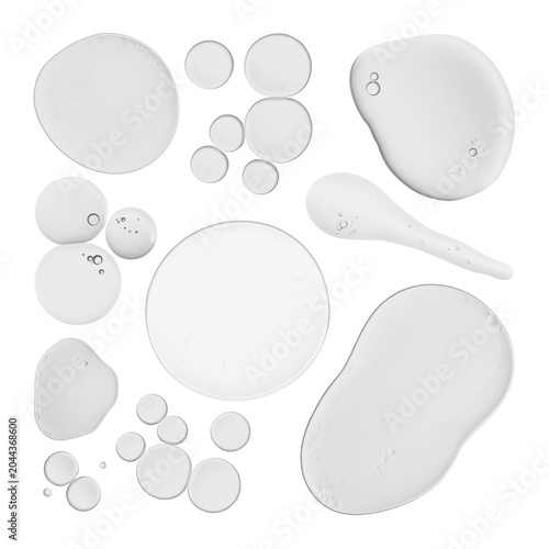 Obraz na plátně Clear liquid drops and smears of various shapes and sizes, possibly cosmetic serum or gel, on a white background