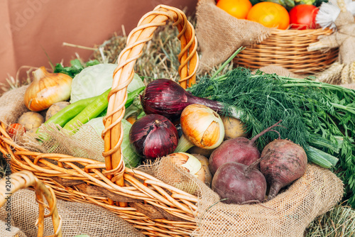 Basket with fresh colorful vegetables and salad on gray wood