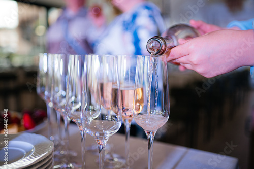 Waiter pouring rose wine into crystal glasses at a gala event