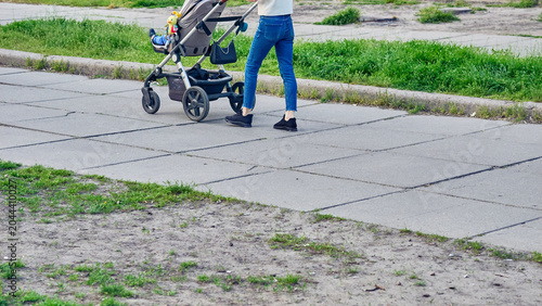 Konstfotografi Legs in jeans of young mother walking with baby stroller
