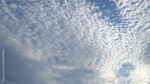 Time-lapse view of small white clouds with shifting light effects in the sky.