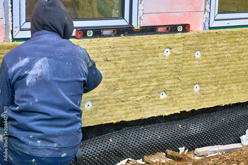 Photos Constructionsite.Worker installs thermal insulation panels