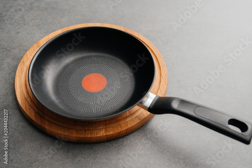 Empty non-stick frying pan on a wooden board
